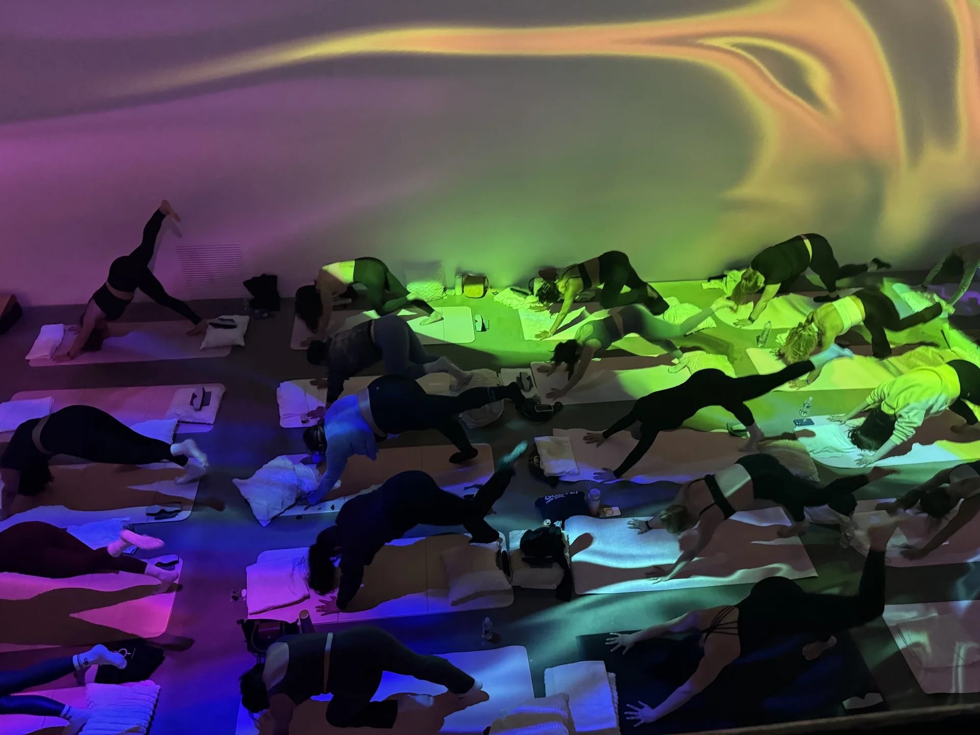 Rainbow aurora projections across participants during yoga flow