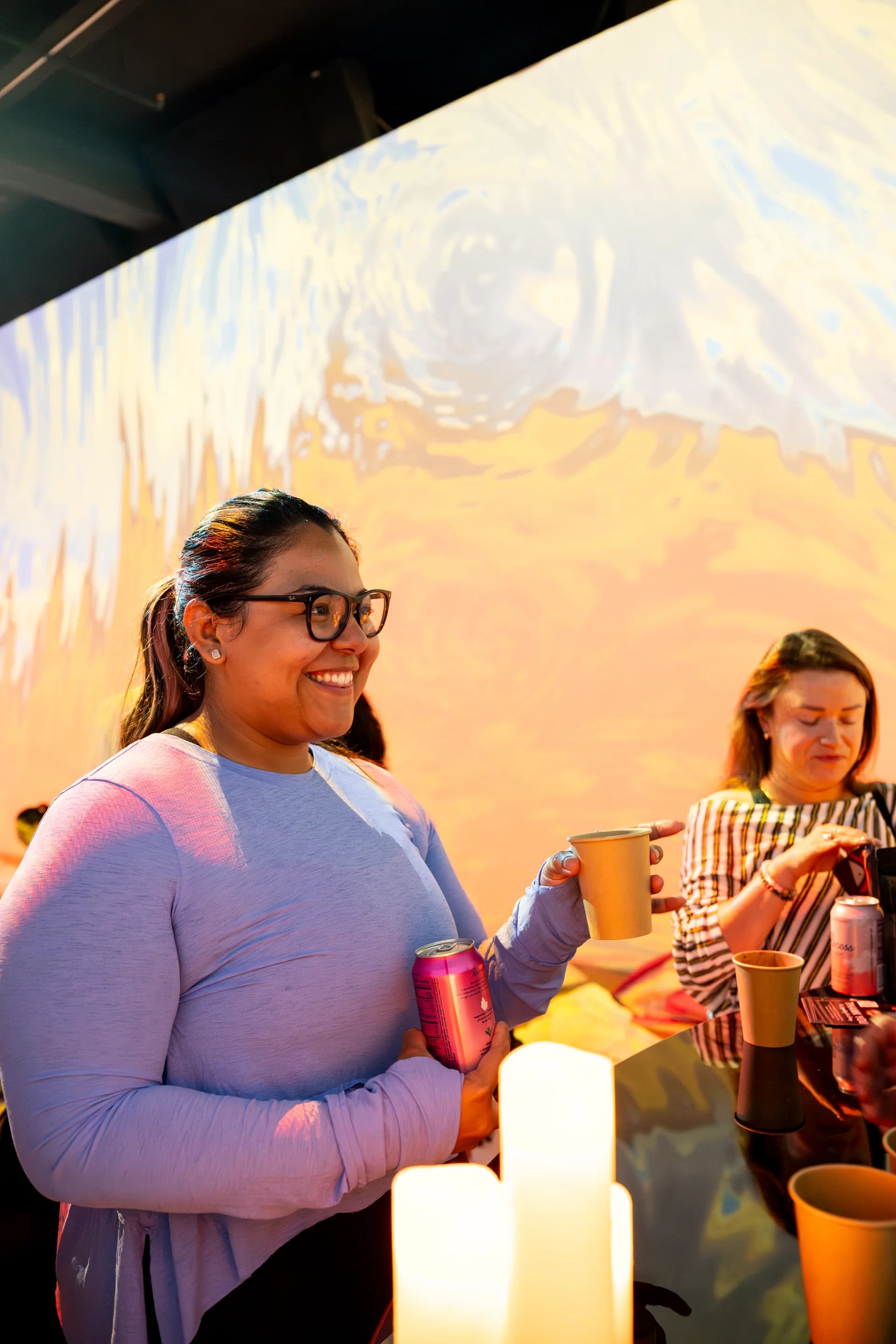 Attendees socializing under warm golden wave projections
